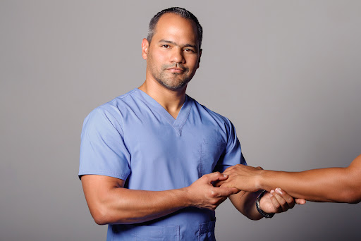 Dr. Germán Delgado examinando la mano y muñeca de un paciente